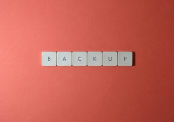 Free Close-up of keyboard keys spelling 'BACKUP' placed on a coral-colored surface. Stock Photo